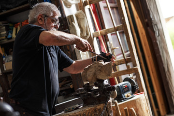 Senior sculptor working on his sculpture in his workshop.