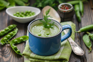 Fresh green pea soup with pea seeds and pea pods . Cream soup of green peas. A delicious lunch in a rustic style
