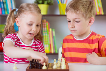 Fototapeta premium Two cute siblings playing chess