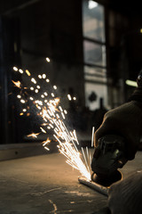 Worker cutting metal with grinder. Sparks while grinding iron