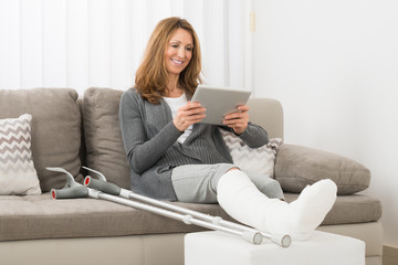 Woman With Fractured Leg Using Digital Tablet