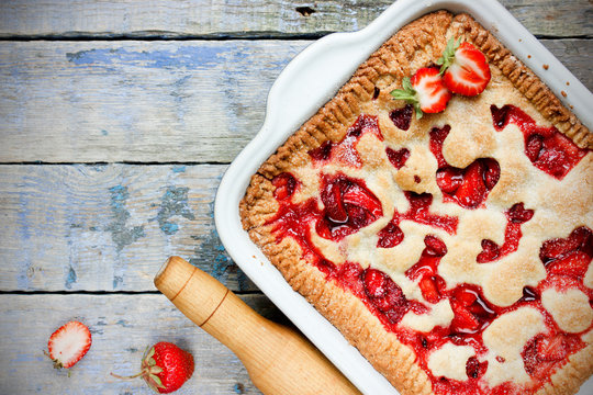 Homemade strawberry pie on old wooden background