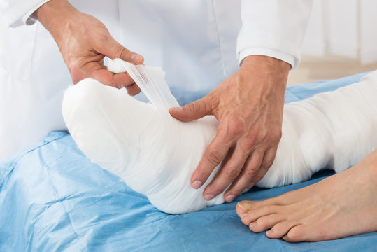 Doctor Tying Bandage On Patient Leg