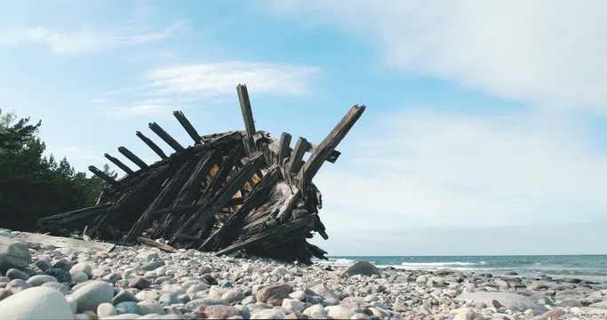 Ship wreck on sloping pebble beach on a calm sunny day