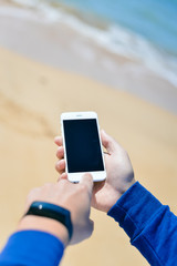 Person holding mobile phone checking connection using watch. Sunny background