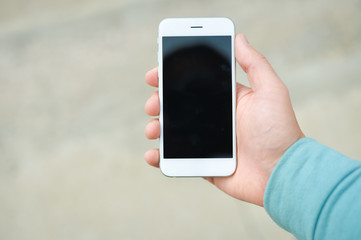 Person using phone over outdoors street background, closeup on hand