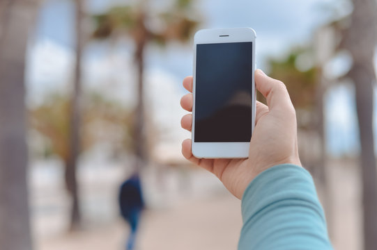 Person using phone against outdoors street background, closeup