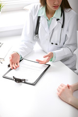 Close up of doctor and  patient  sitting at the desk near the window in hospital