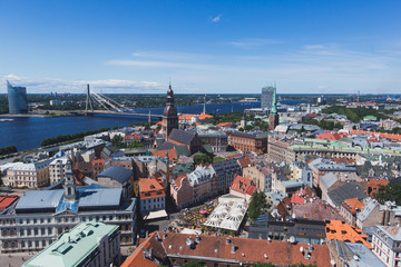 Fototapeta na wymiar Beautiful super wide-angle panoramic aerial view of Riga, Latvia with harbor and skyline with scenery beyond the city, seen from the St. Peters Church observation tower, sunny summer day