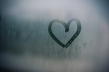 Sign of love heart on glass. The window is fogged up background