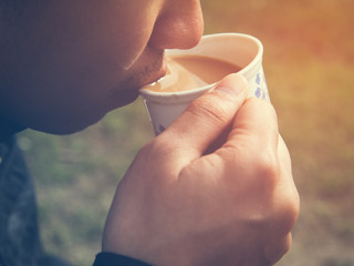 Man drinking a cup of masala chia tea with warm light