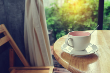 Coffee mug on wooden table with green bokeh background.