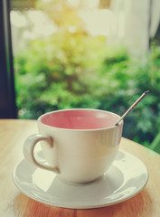 Coffee mug on wooden table with green bokeh background.