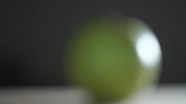 Man hand placing wet green apple and cutting it with a big knife, rack focus