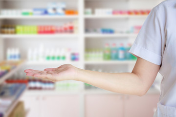 female pharmacist with blur shelves filled with medication in th