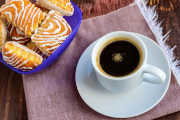 Crispy puff cookie with white chocolate and black coffee cup on a wooden background