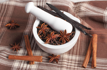 Fragrant cloves and anise in mortar and spices on rustic board
