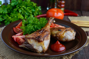 Roasted goose leg, sauce, herbs and tomatoes in a clay bowl on wooden background