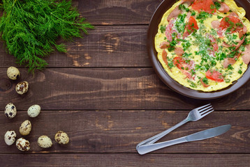 Omelet with sausage and fresh tomatoes and herbs on a clay plate