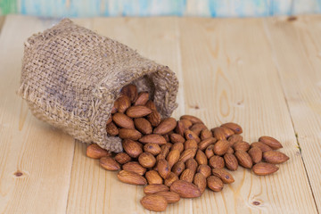 Almonds in brown bowl on textured wooden background