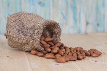 Almonds in brown bowl on textured wooden background