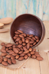 Almonds in brown bowl on textured wooden background