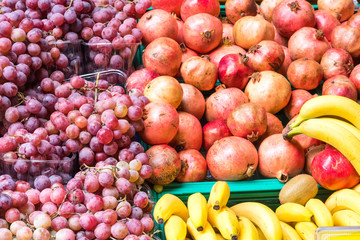 Naklejka na ściany i meble Grapes, bananas and pomegranate for sale at a market