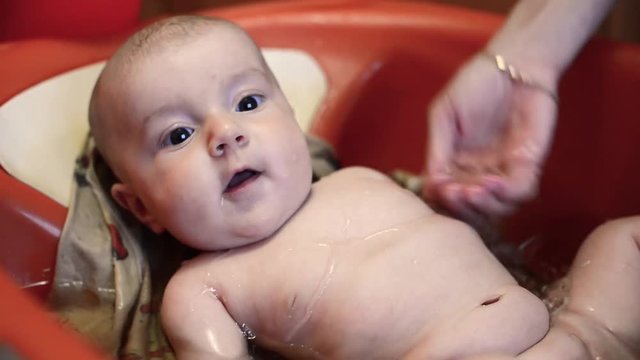 cute little baby lying in bath and look in the camera slow motion