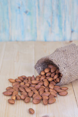 Almonds in brown bowl on textured wooden background
