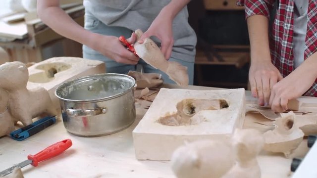 Tilt up of two young female artists making papier mache dog figures of craft paper together at small handmade studio, shaky camera shot on Sony NEX 700 + Odyssey 7Q