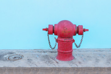 Old red Fire Hydrant on footpath with blue walls freshly painted.
