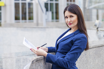 Obraz premium Young beautiful woman in a blue jacket signs the contract