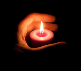 hand holding a burning candle in dark