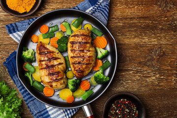 Grilled chicken breast with vegetables in a pan.