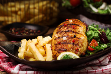 grilled chicken breast with green salad and french fries.