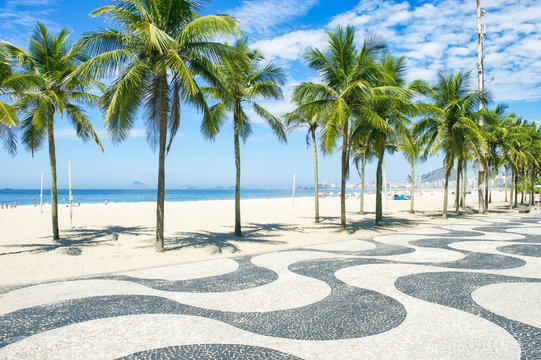 Iconic curving sidewalk tile pattern with palm trees at Copacabana Beach, Rio de Janeiro, Brazil 