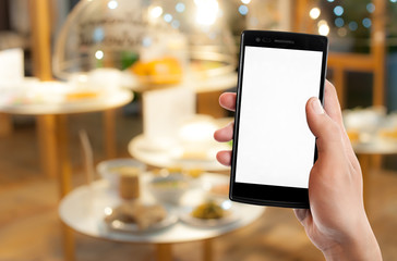 Hand holding smart phone on blurred food background,
