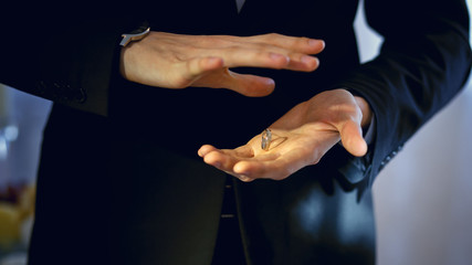 Obraz premium magician in a black suit holds a ring between his hands