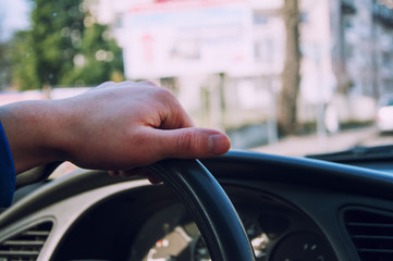 Hands of a driver on steering wheel of a car in the city