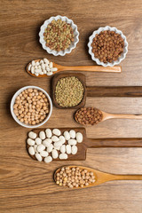Legumbres variadas sobre cuenco y cucharas de madera rústica. Vista superior.