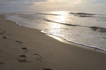 Footprints in the sand and sunset on the sea