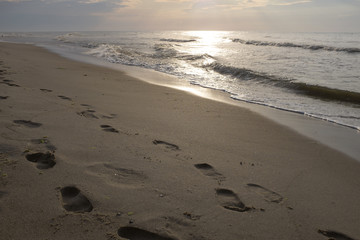 Footprints in the sand and sunset on the sea