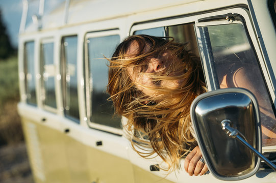 Teen girl sticking head out of van in motion