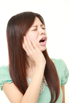 young Japanese woman wearing a green summer dress suffers from toothache