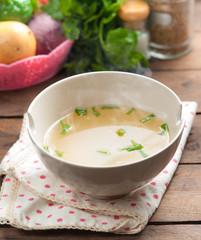 bowl of broth and fresh vegetables on wooden