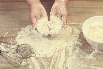 Manos con harina vista desde arriba sobre una mesa rústica  de madera. Vista superior