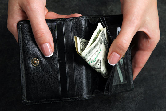 small money in the wallet on the black background in the hands of women.The concept of poverty