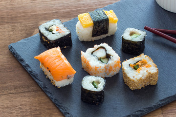 Sushi Set sashimi and sushi rolls served on stone slate