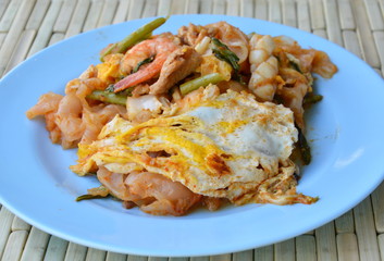 stir fried rice noodle seafood and egg with sukiyaki sauce on dish