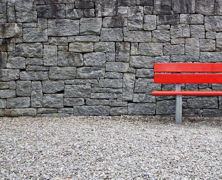 Red bench and brick wall. Long chair for relax in garden. Long bench with red color with brick wall at home for read book and relexing.